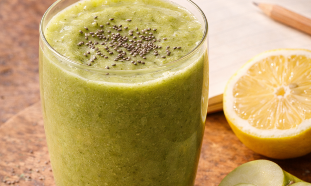 Verre de smoothie vert frais aux graines de chia, pomme et concombre, posé sur une table en bois à côté d'un carnet de recettes ouvert. Smoothie Ventre Léger